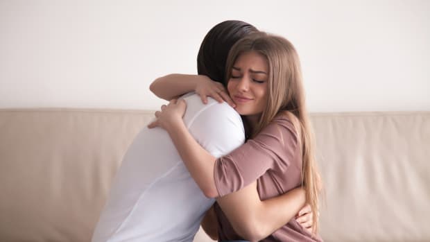 Portrait of emotional young couple hugging each other tightly, boyfriend and girlfriend embracing sitting on couch, reconciliation after argument, love you so much, strong affection in relationships