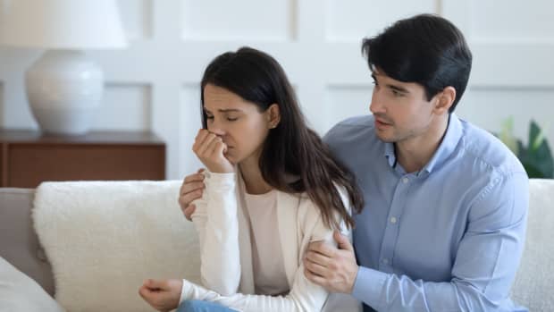 Affectionate caring young man embracing stressed young woman, overcoming problem together. Loving guilty millennial guy asking forgiveness to anxious crying depressed offended girlfriend indoors.