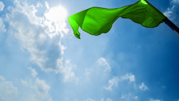 Green flag on a background of the dark blue sky with clouds.