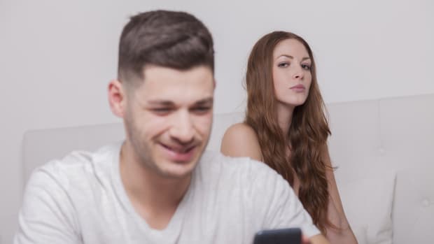 man receives a message on the smart phone while woman looks jealous