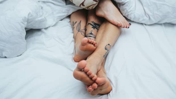 tattooed feet in bed together