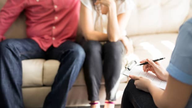Professional female psychologist making notes of married couple during therapy session